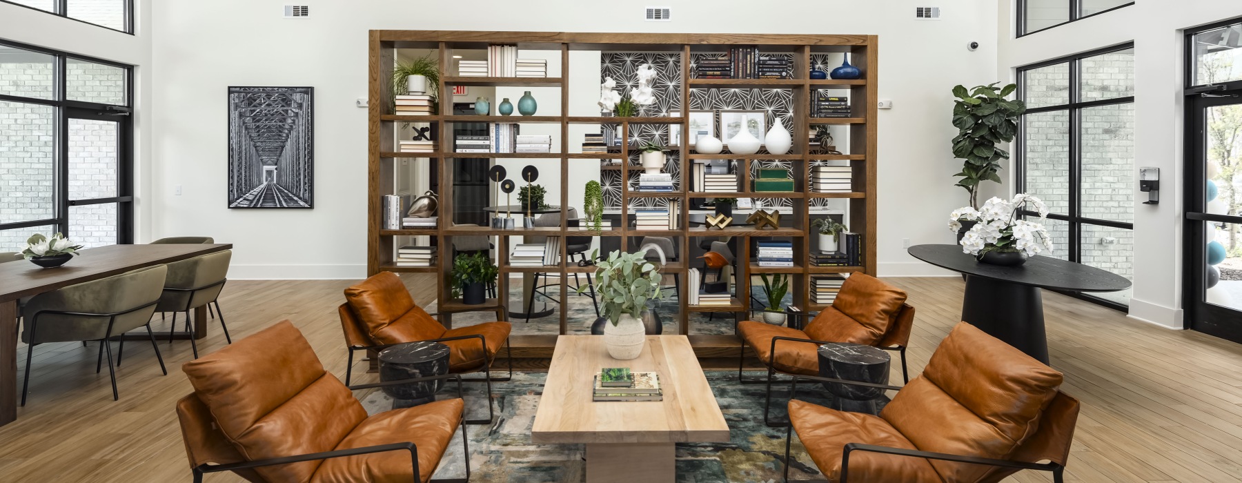 Shared common space with tables, chairs, and bookcases at Arcadia Symphony Park Apartments near Atlanta